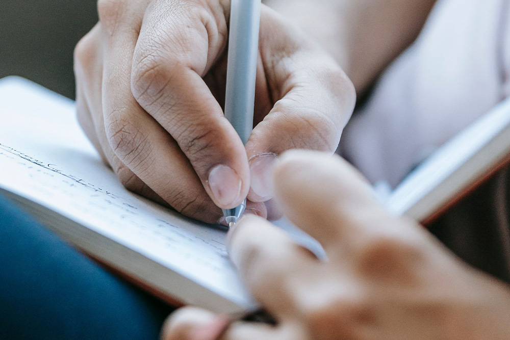 An author writing in a notebook to suggest how to improve your character personality strengths and weaknesses