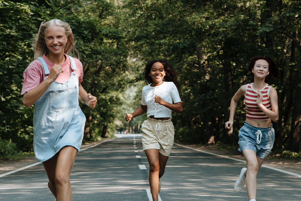 Teenagers running across an open road to suggest how young adult fiction can be empowering and light