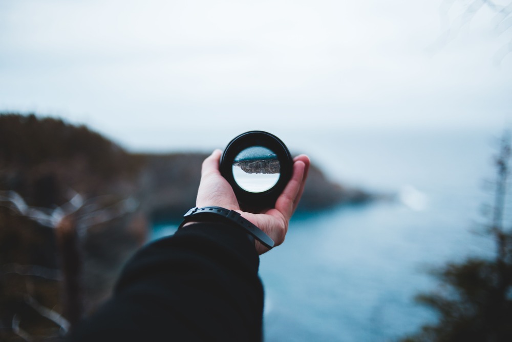 A lens being used to focus a blurry image, playing a similar role to point of view in literature.